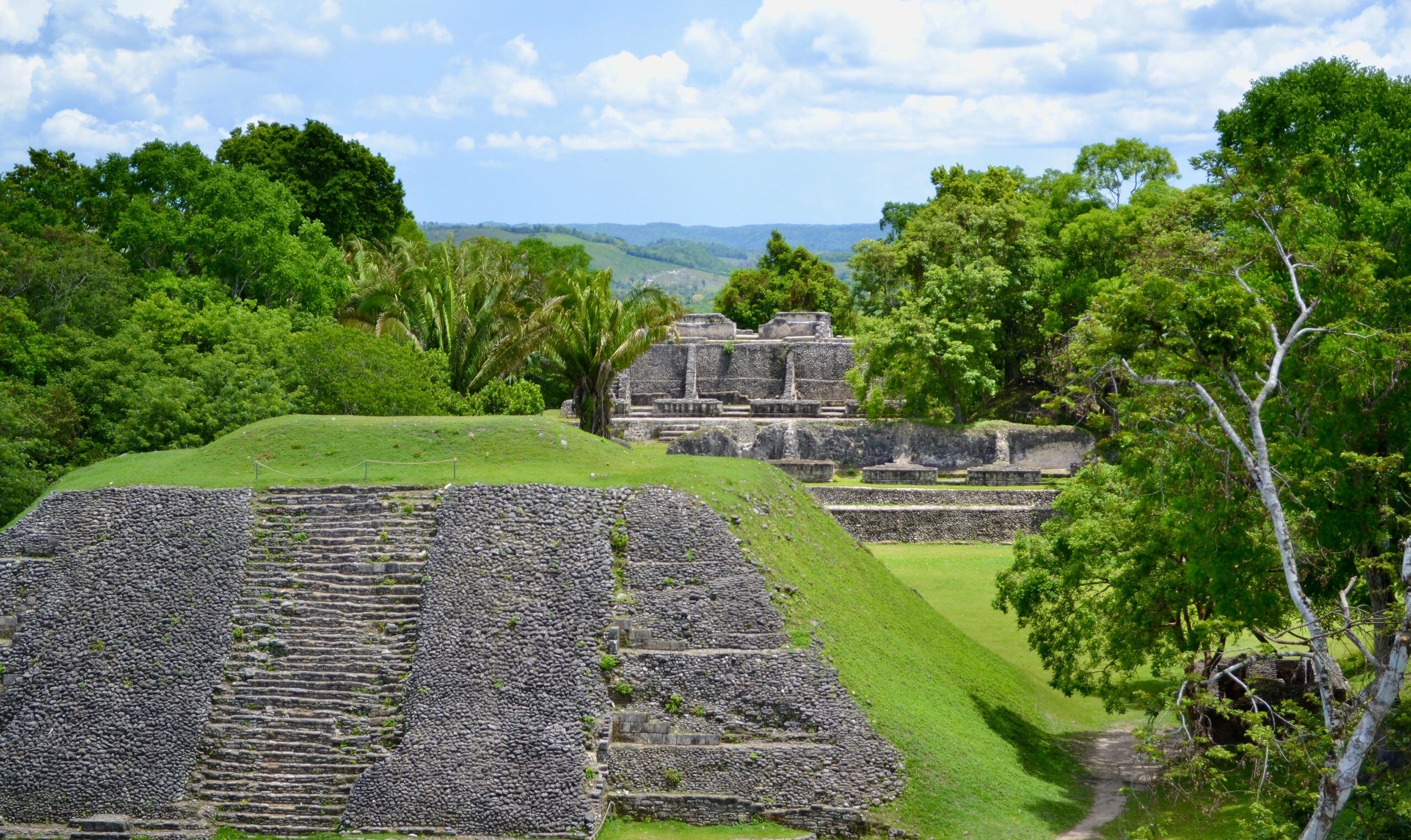 Lush green hills of Belize and Mayan structures on a bright blue day