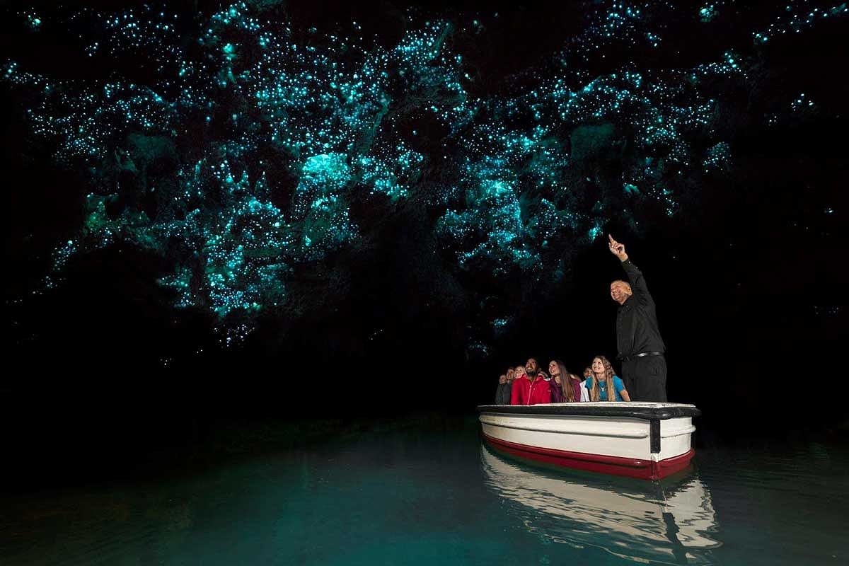 People ride a boat through the Waitomo Caves in NZ